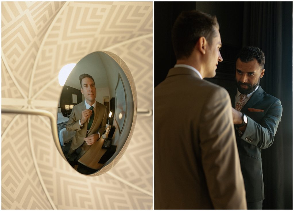A groom adjusts his tie in a mirror.