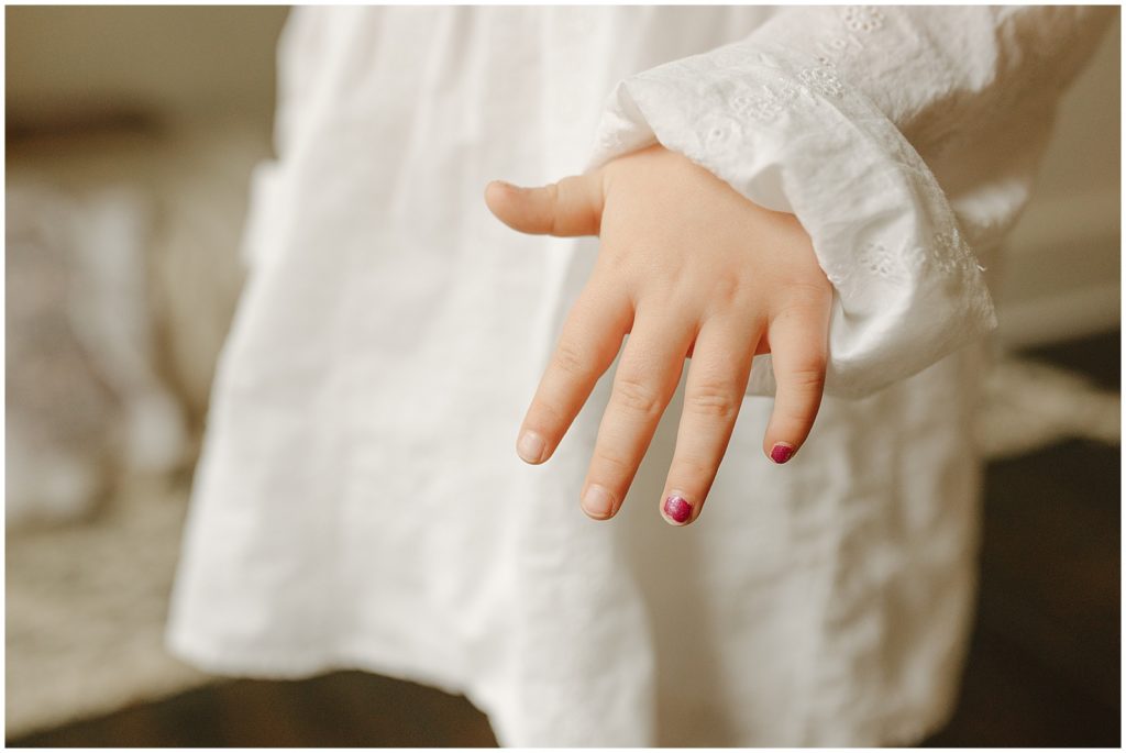 A toddler holds out her hand to show a painted fingernail.
