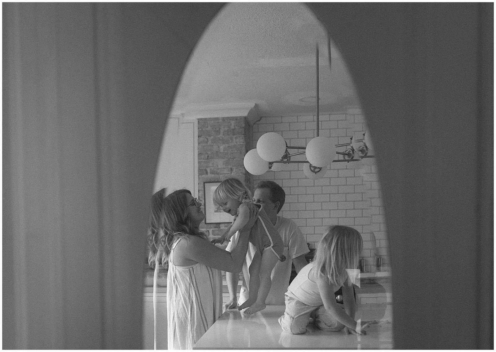 Through a door, a family plays in documentary family photos.