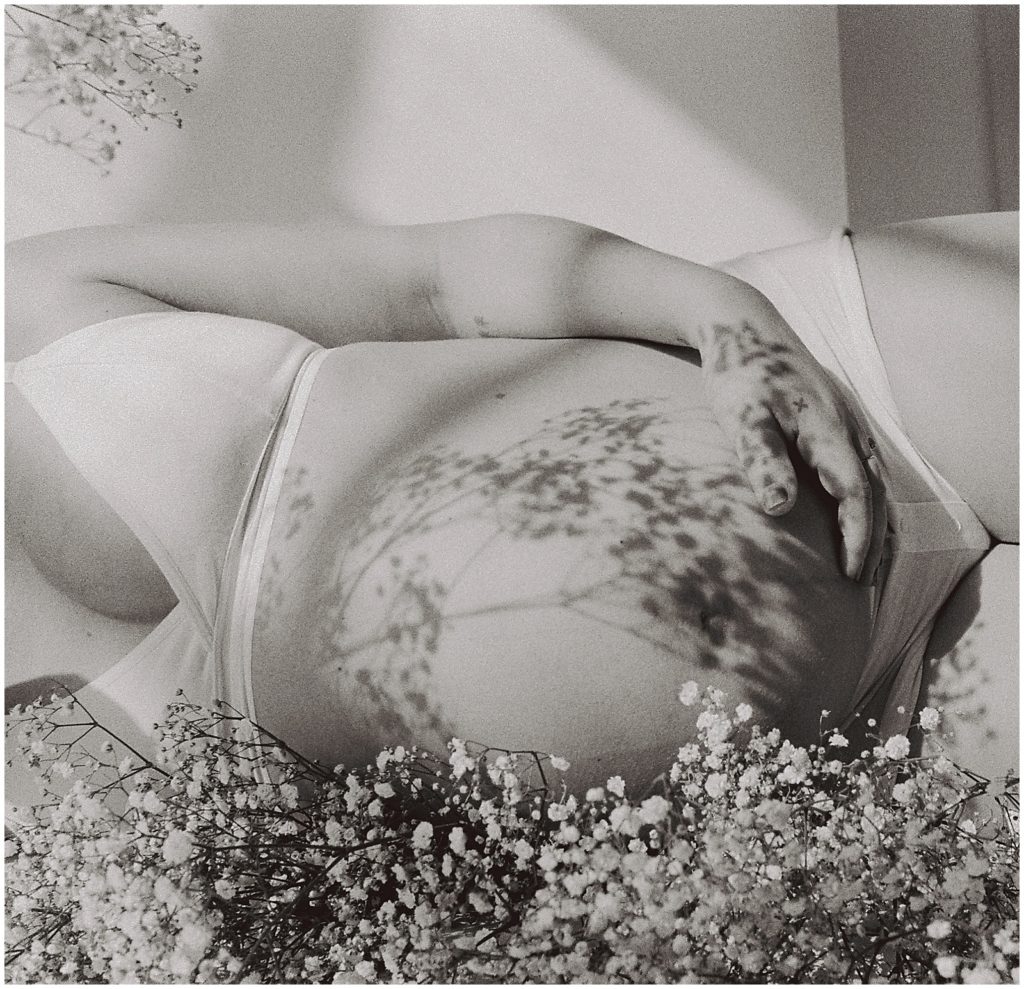 Baby's breath flowers cast a shadow on Nicole's baby bump in her studio maternity photos.