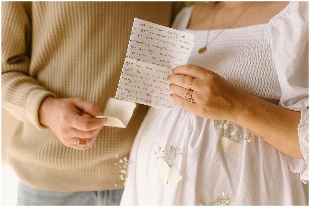 Nicole and Ethan open their letters to each other during their studio maternity photos.
