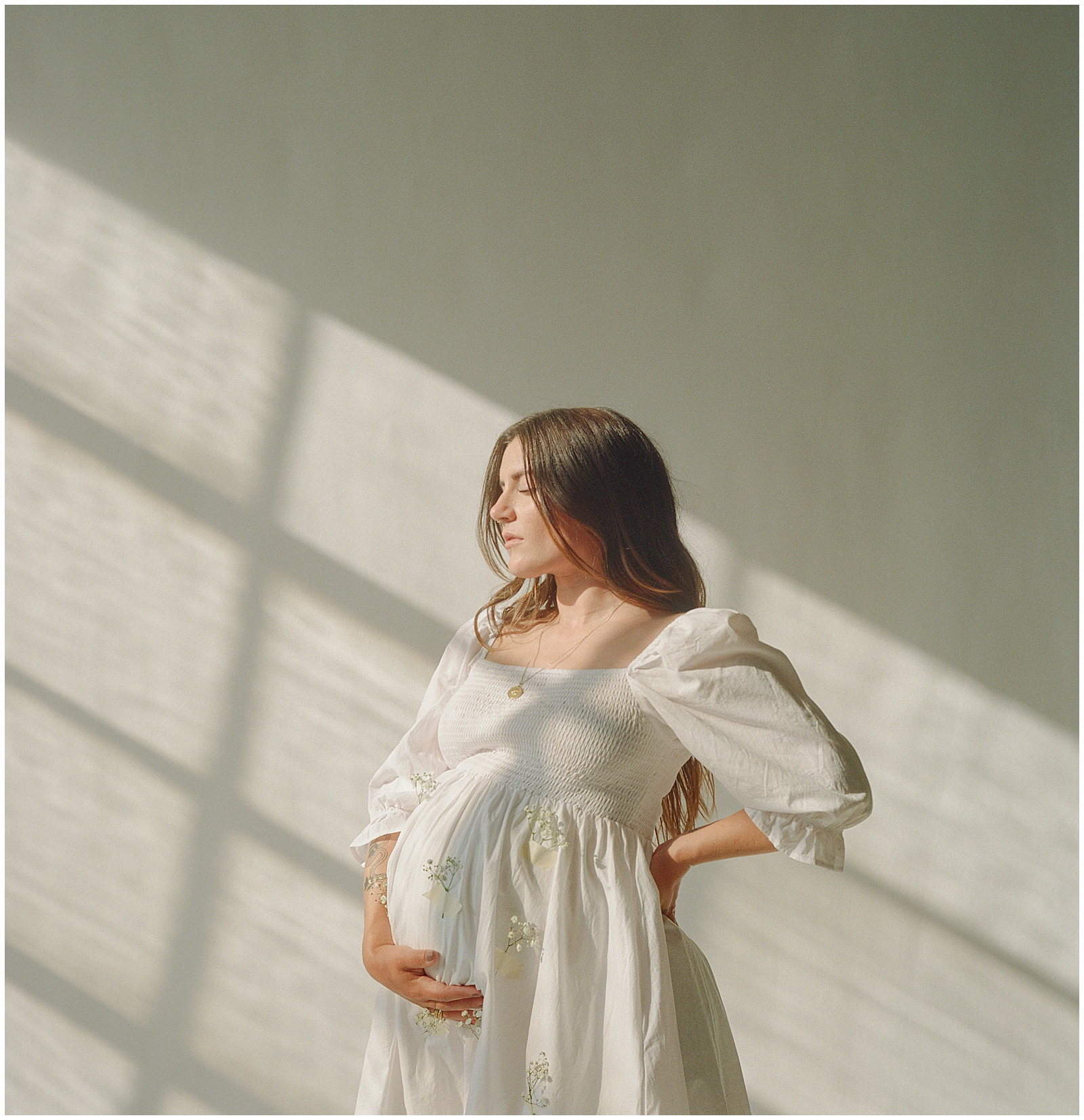 Nicole puts a hand on her baby bump in her studio maternity photos.
