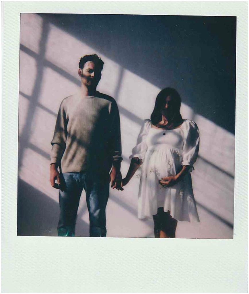Ethan and Nicole hold hands and walk towards the Polaroid camera.