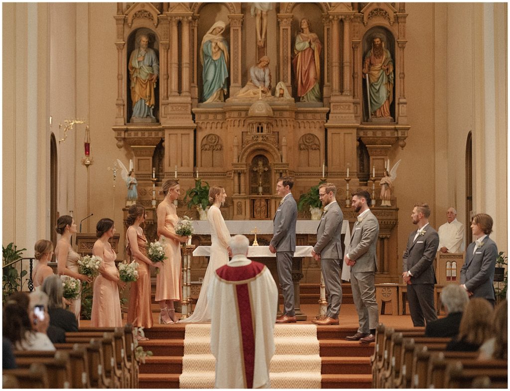 A priest walks up the aisle towards the wedding ceremony.