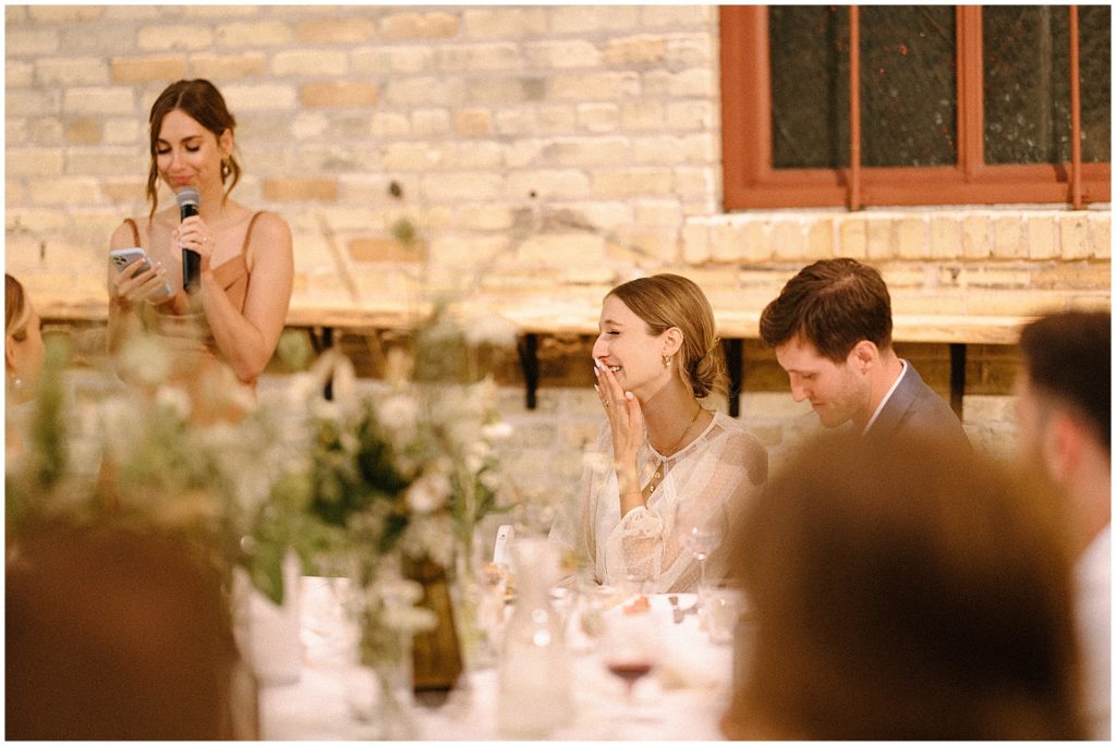 Sarah puts a hand to her mouth during her friend's wedding toast at The Cooperage.