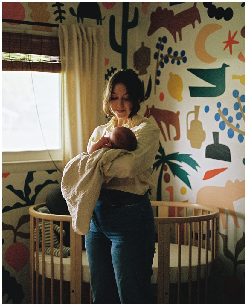 Mother holding her newborn in a colorful nursery