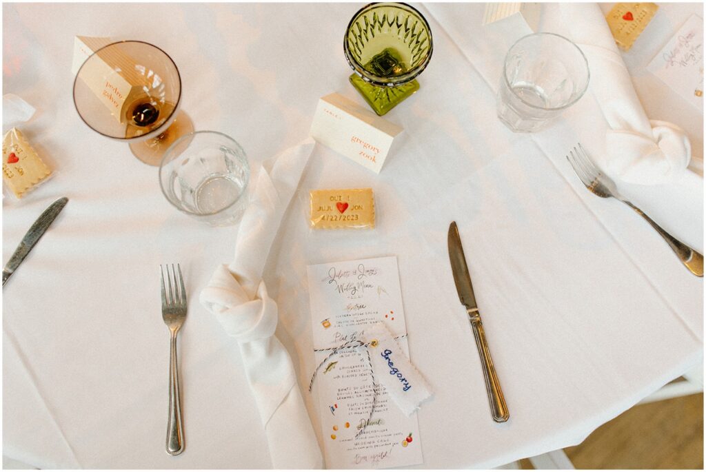 A wedding reception table includes cross-stitched place cards.