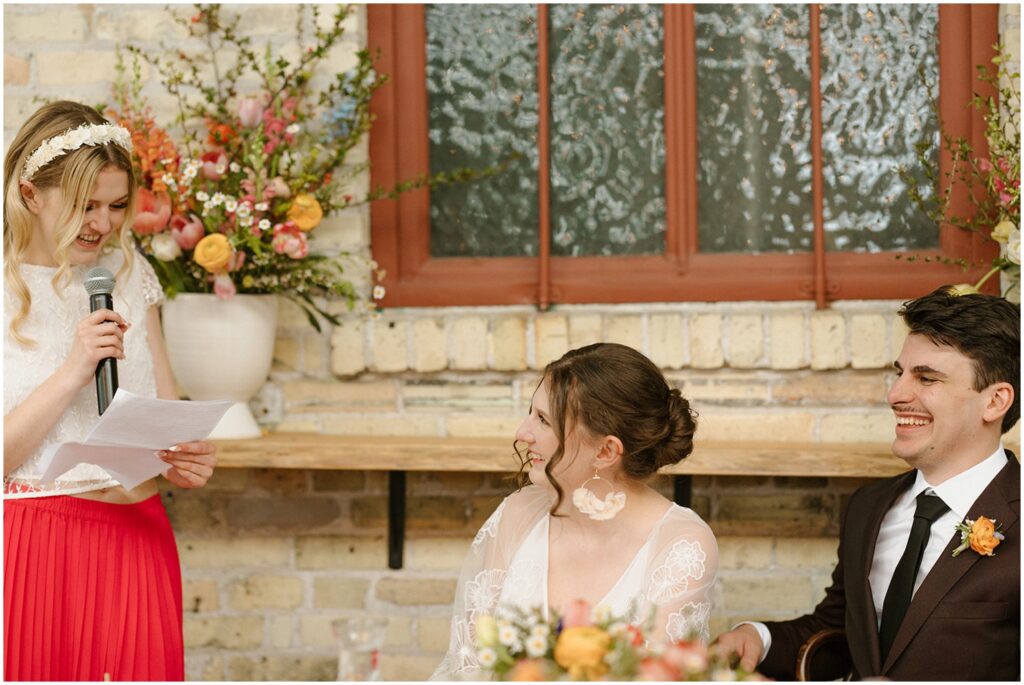 A bride and groom laugh during a bridesmaid speech.