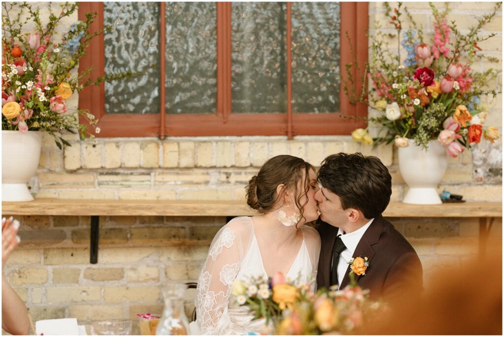 A bride and groom kiss at their reception table at Villa Terrace Milwaukee.
