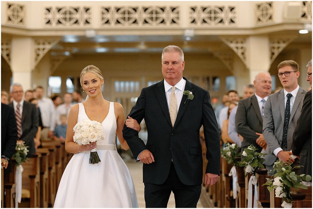 A bride and her father walk a processional at a Milwaukee church wedding.