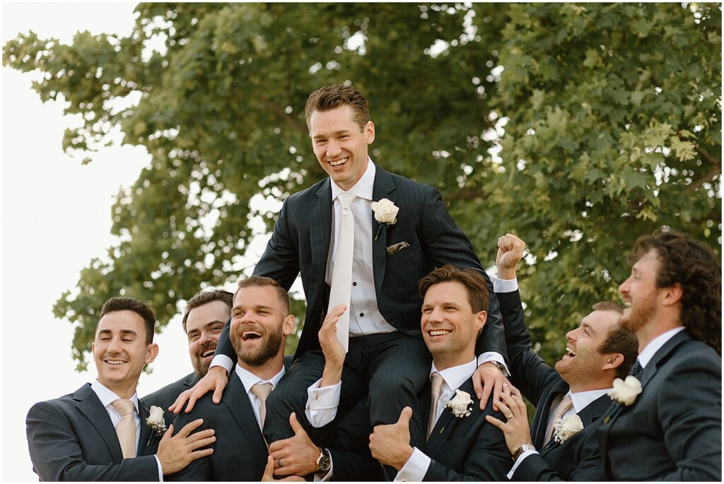Groomsmen lift a Milwaukee groom on their shoulders.