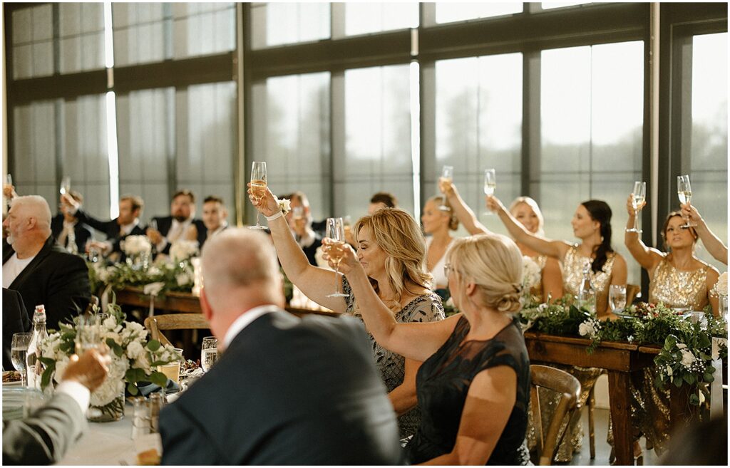 Guests raise their glasses during a wedding toast.