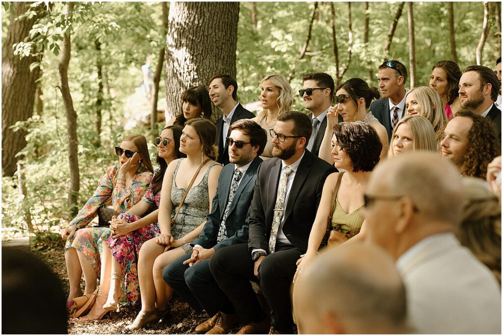 Wedding guests sit in white chairs at the Urban Ecology Center.