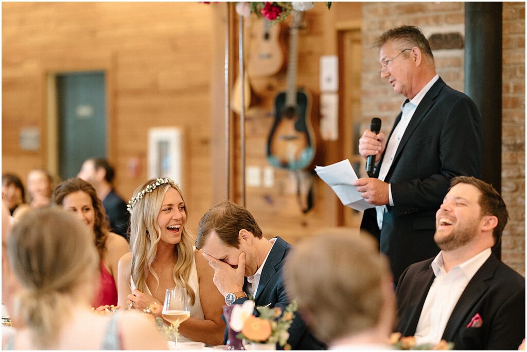 A bride and groom laugh at the father-of-the-bride speech at their Milwaukee wedding.