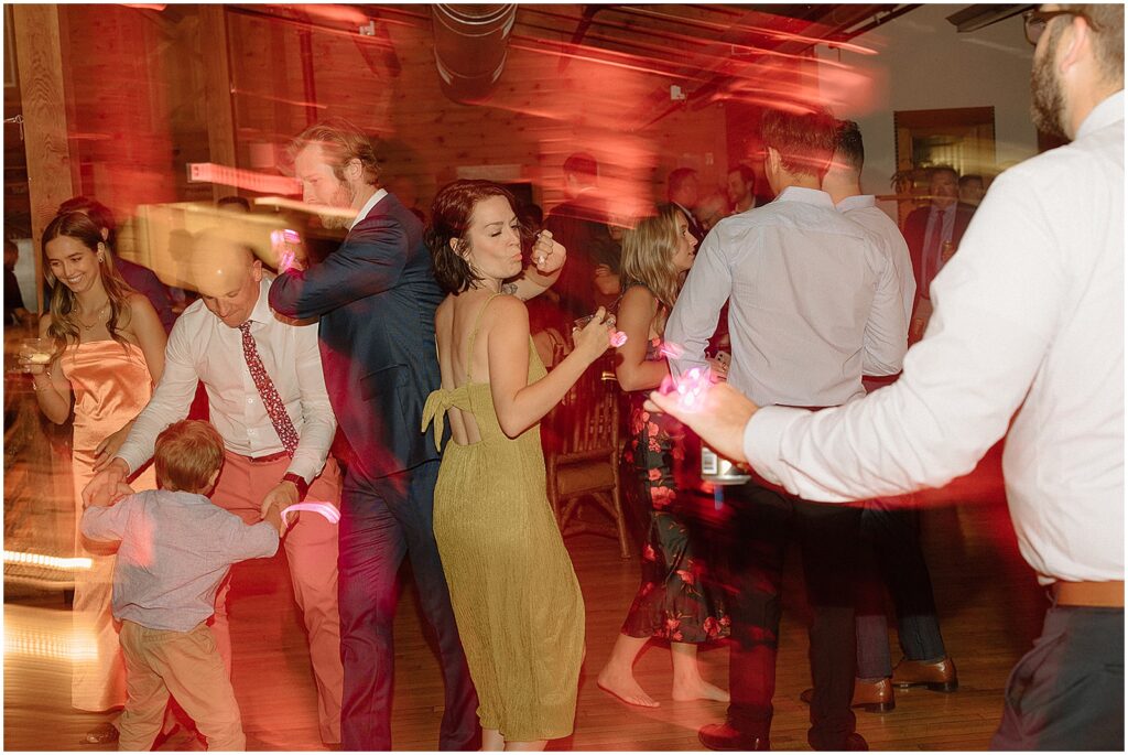 Wedding guests dance with blurred red lights around them.