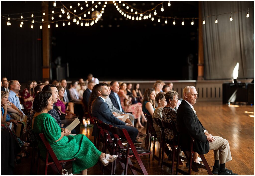 Wedding guests sit beneath strings of lights for a Turner Hall wedding.