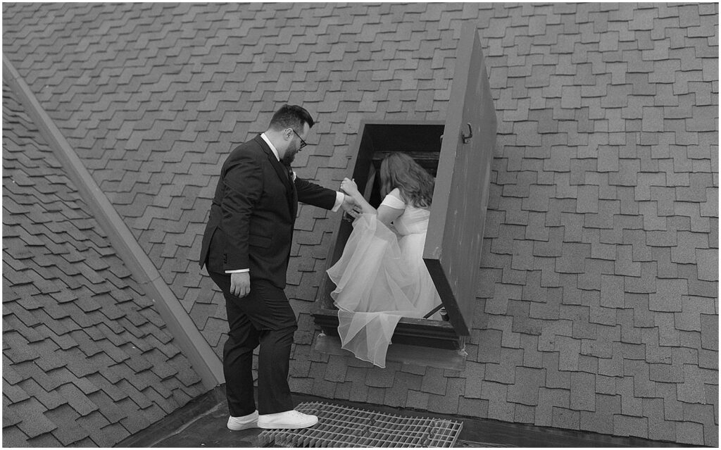 A groom helps a bride climb through a window on the rooftop of Turner Hall in Milwaukee.