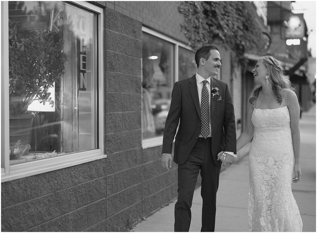 A bride and groom hold hands and walk down the sidewalk outside Dandy Milwaukee.
