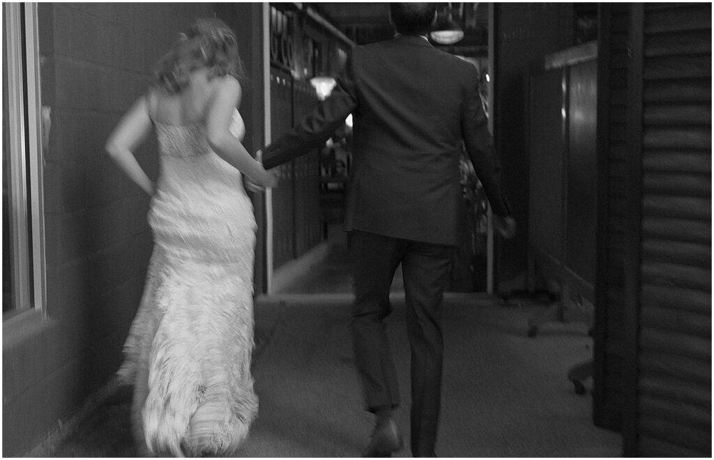 A bride and groom run towards their Milwaukee wedding reception.