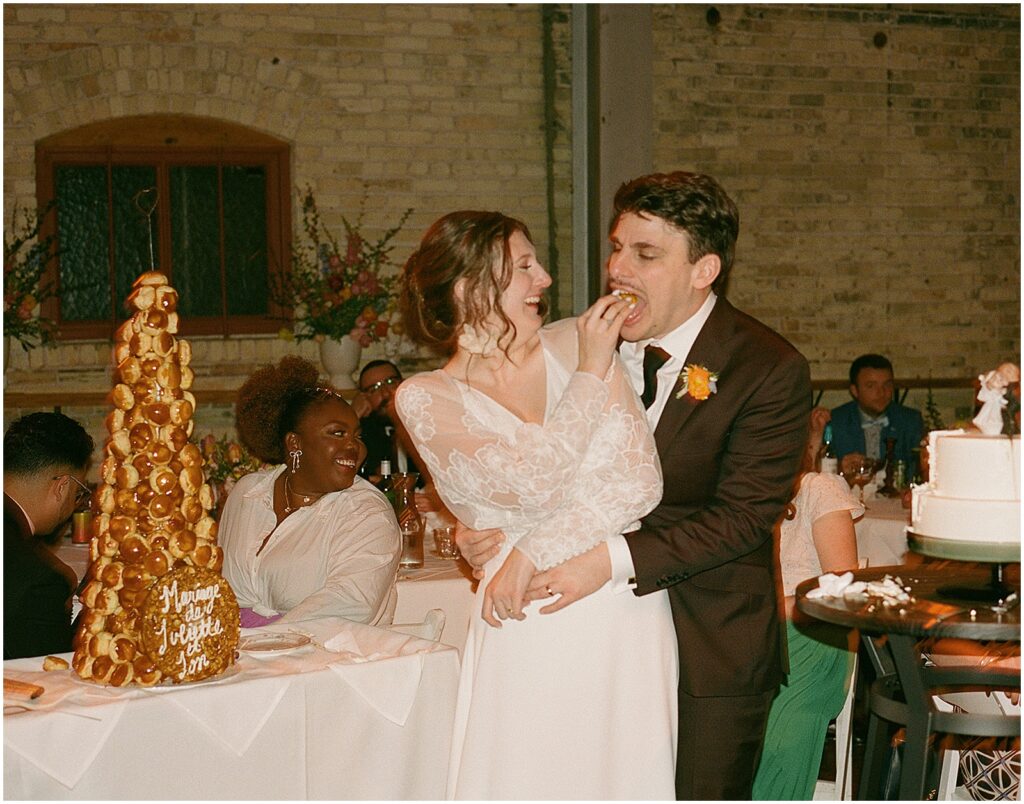 A bride feeds a pastry to a groom at their Milwaukee wedding.