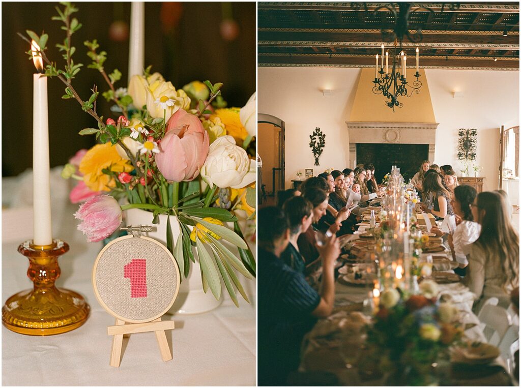Guests sit at a long table lined by flowers and candles in a film wedding photo.