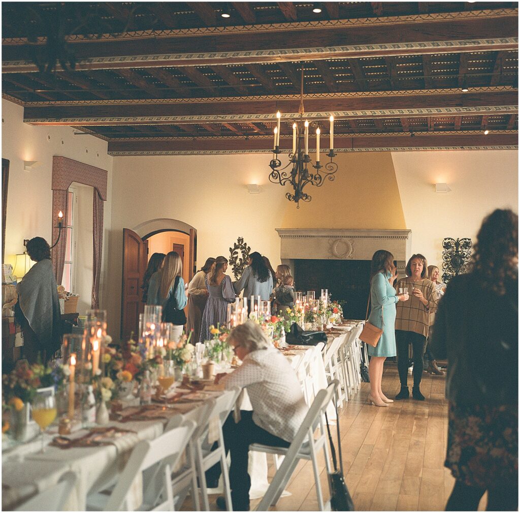 Baby shower guests walk around a table inside Villa Terrace.
