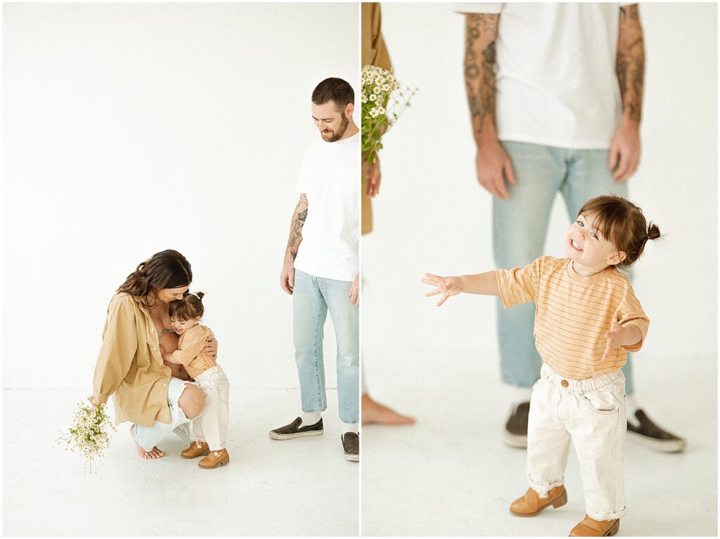 A pregnant woman kneels to hug her toddler during a studio maternity session.