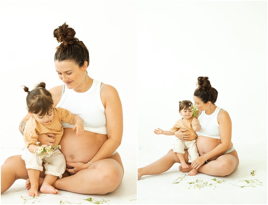 A pregnant woman sits with her toddler and looks at flowers in a Milwaukee maternity photography session.