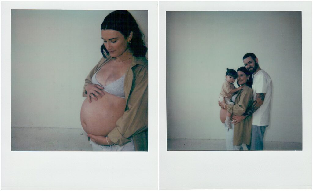 A pregnant woman looks down at her baby bump in a maternity photo on Polaroid film.