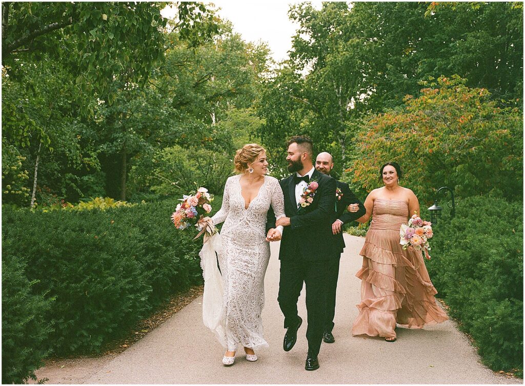 A bride and groom leads their wedding party down a path at a garden wedding.