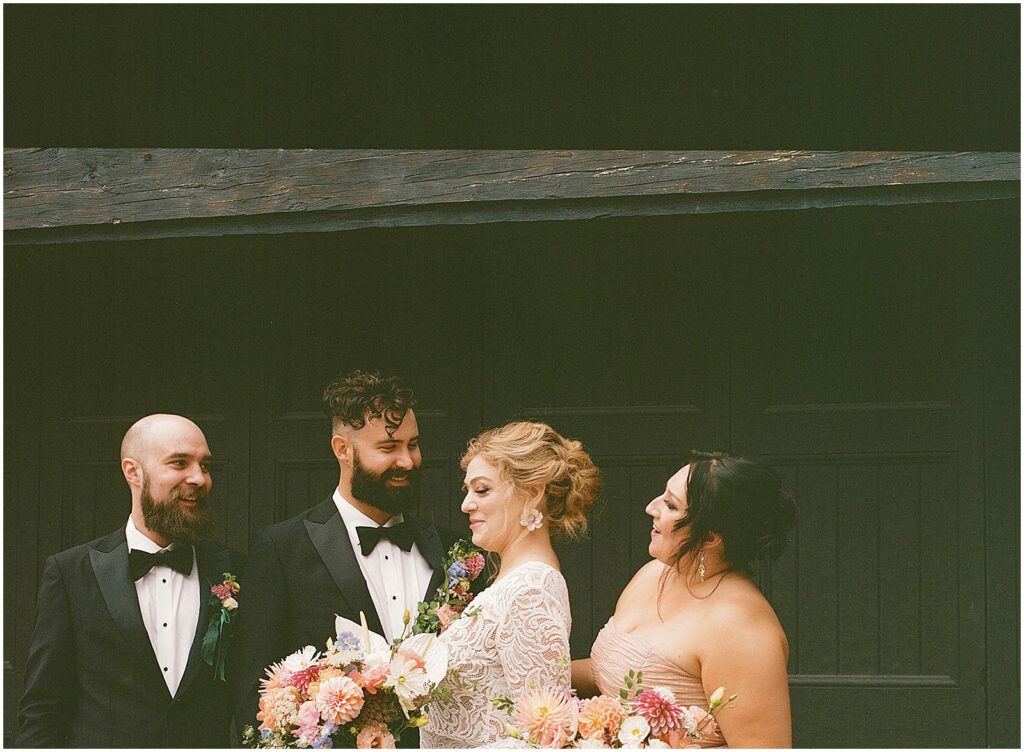 A bride and groom laugh with their wedding party before a summer wedding.