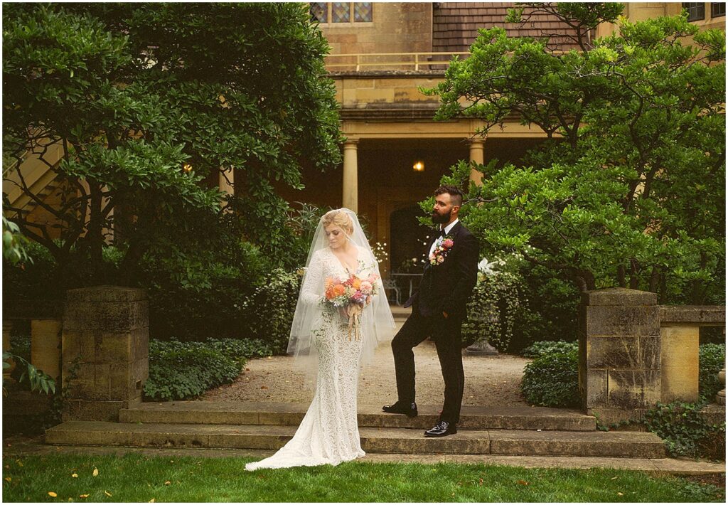 A bride and groom pose for film wedding photography on a garden step.
