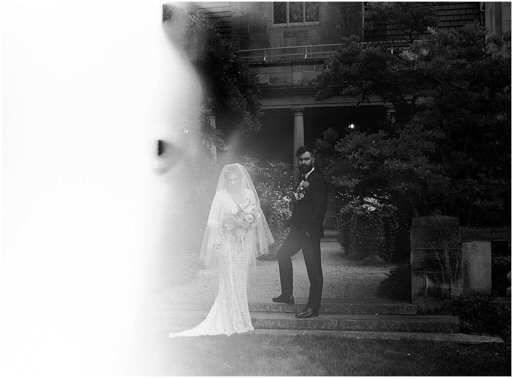 A bride and groom stand for a black and white wedding photo on film.