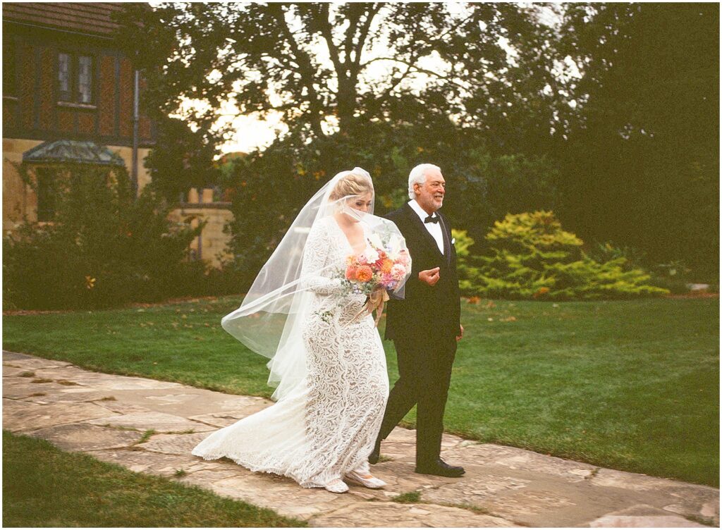 A bride's father walks her towards her Paine Art Center wedding.
