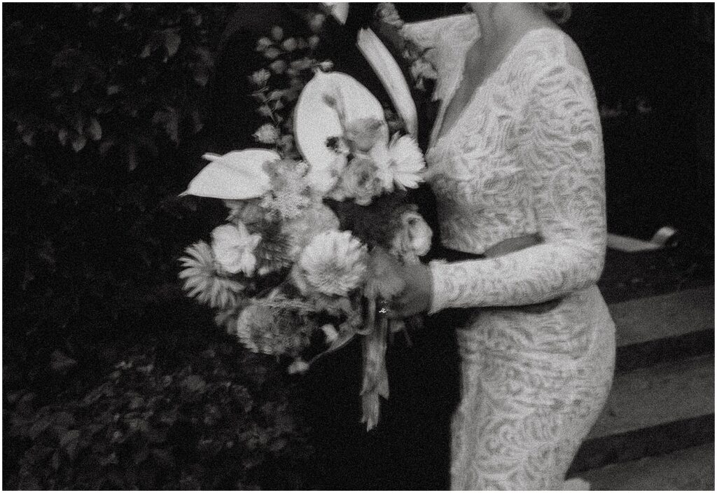 A bride and groom embrace in a black and white film wedding photo.