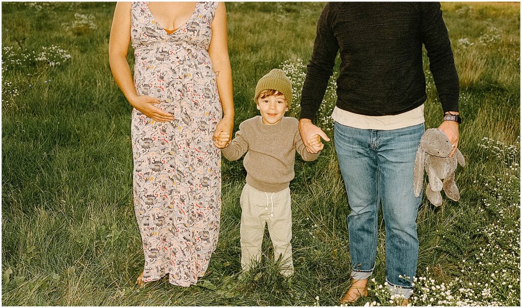 A man and woman hold a child's hand during a mini session on film photography.