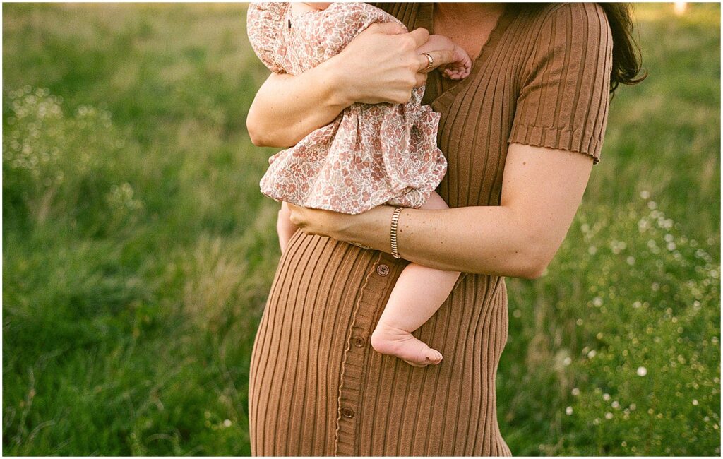 A woman carries a baby on her hip in a photography mini session.