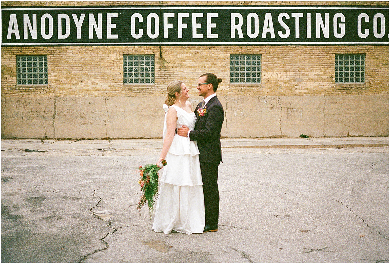 A bride and groom pose outside of Anodyne Coffee in Milwaukee