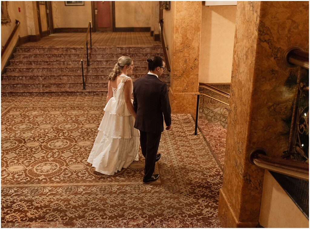 A bride and groom walk through the lobby of the Pfister Hotel.