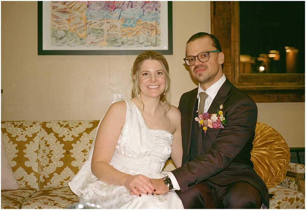 A bride and groom sit on a vintage couch before their wedding at Anodyne Coffee.