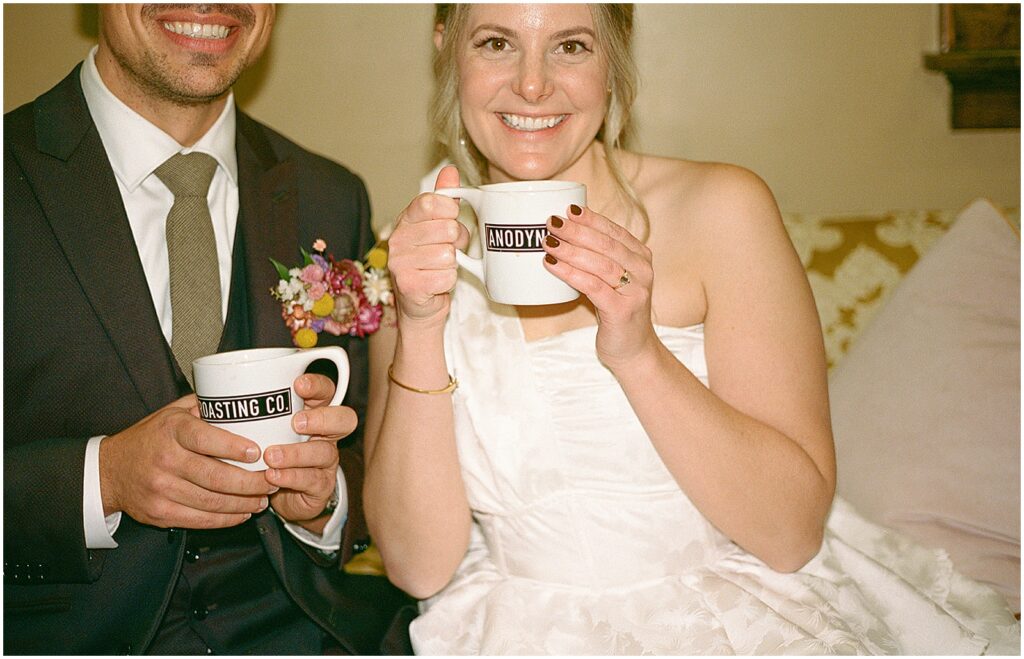 A bride and groom pose with coffee mugs at Anodyne Coffee