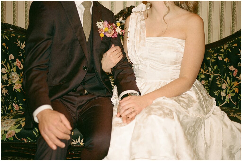 A bride and groom sit side by side holding hands before their Milwaukee wedding.