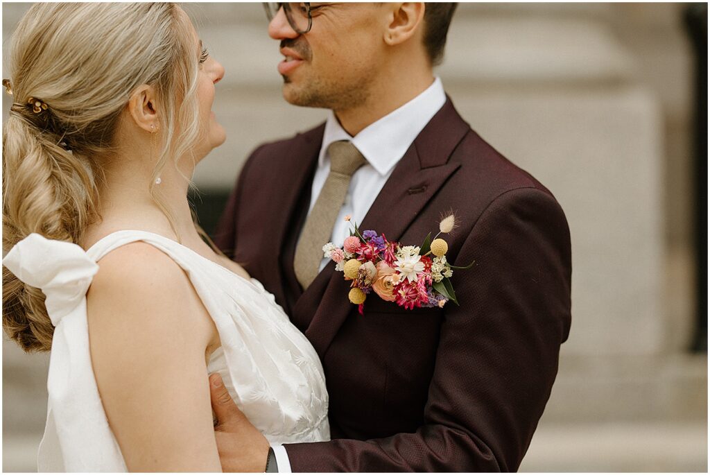 A groom wears a boutonnière of colorful flowers.