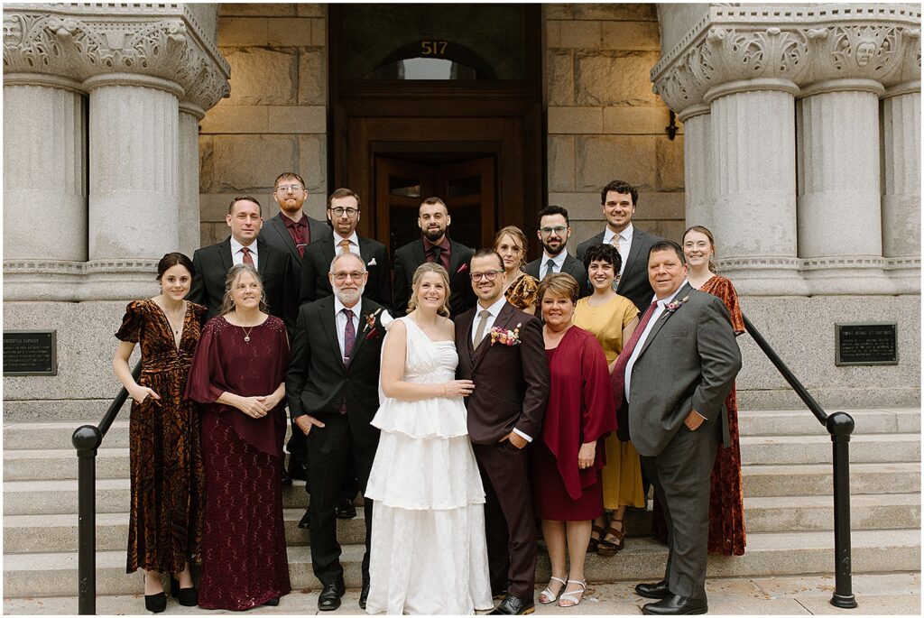 A bride and groom pose with family members on the steps of a Milwaukee hotel.