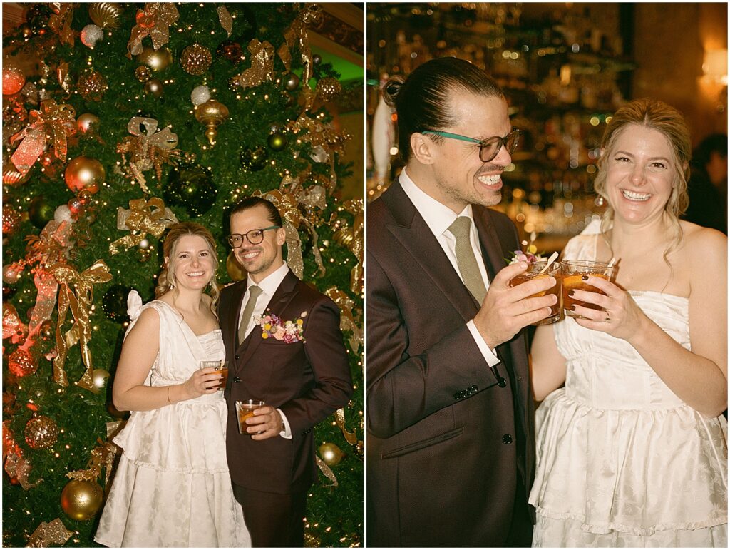 A bride and groom pose in front of a Christmas tree before their winter wedding.