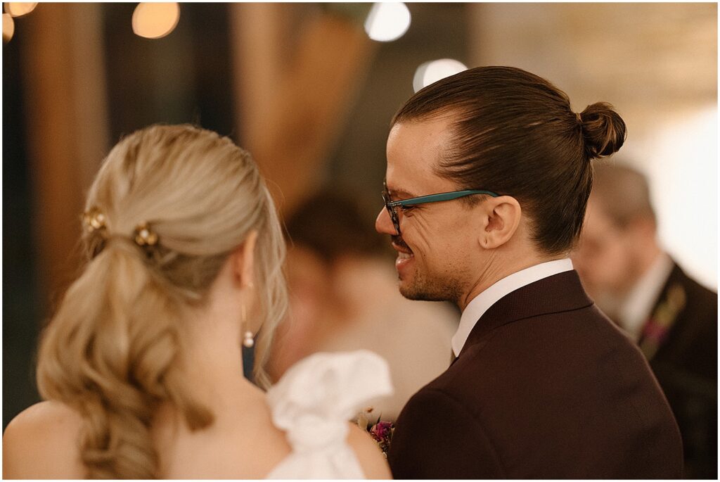 A bride and groom lean towards each other in a candid wedding photo.