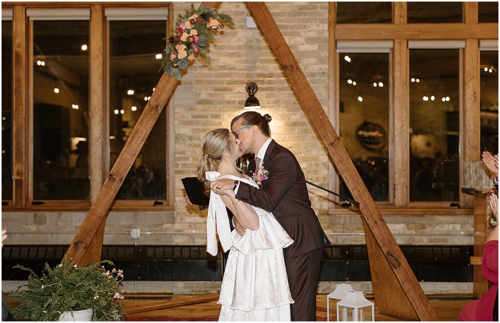 A bride and groom kiss at the end of their Anodyne Coffee wedding.