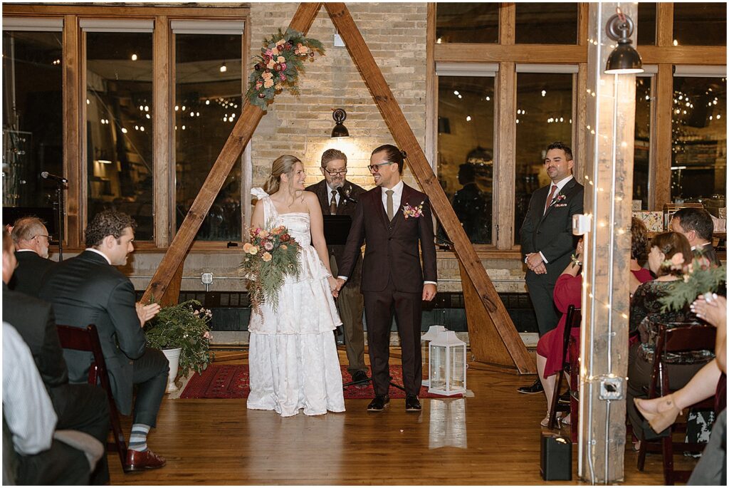 A bride and groom turn to face their wedding guests at the end of their Anodyne Coffee wedding ceremony.