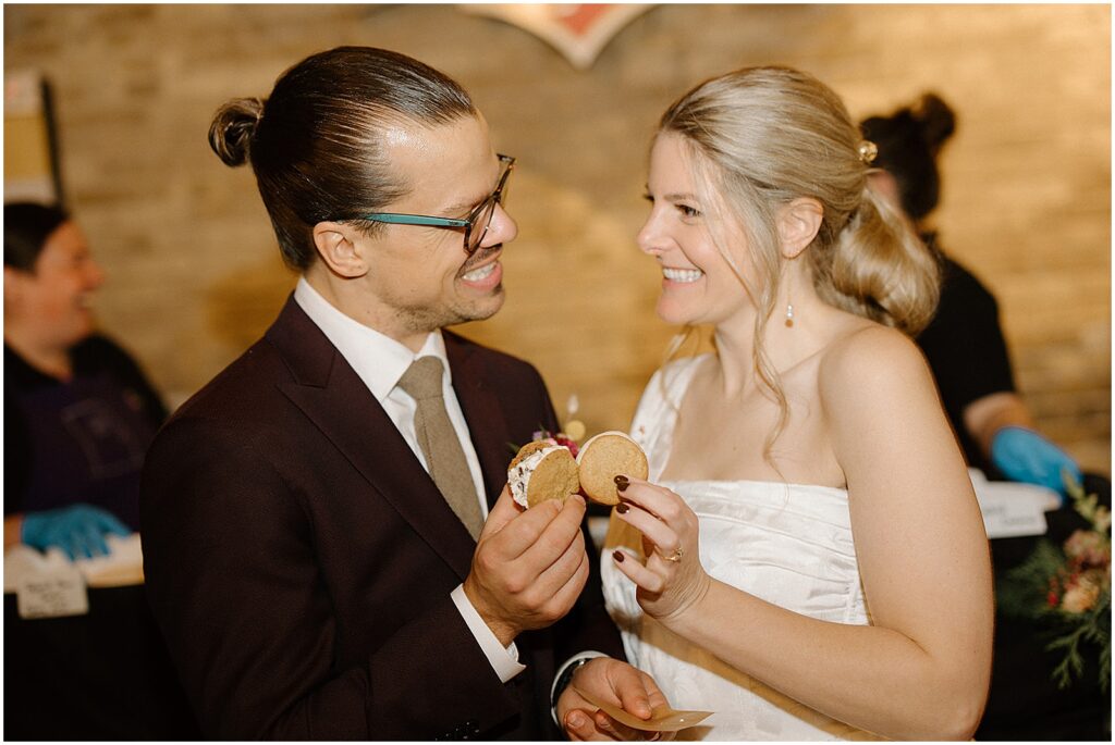 A bride and groom toast with cookies during cocktail hour.