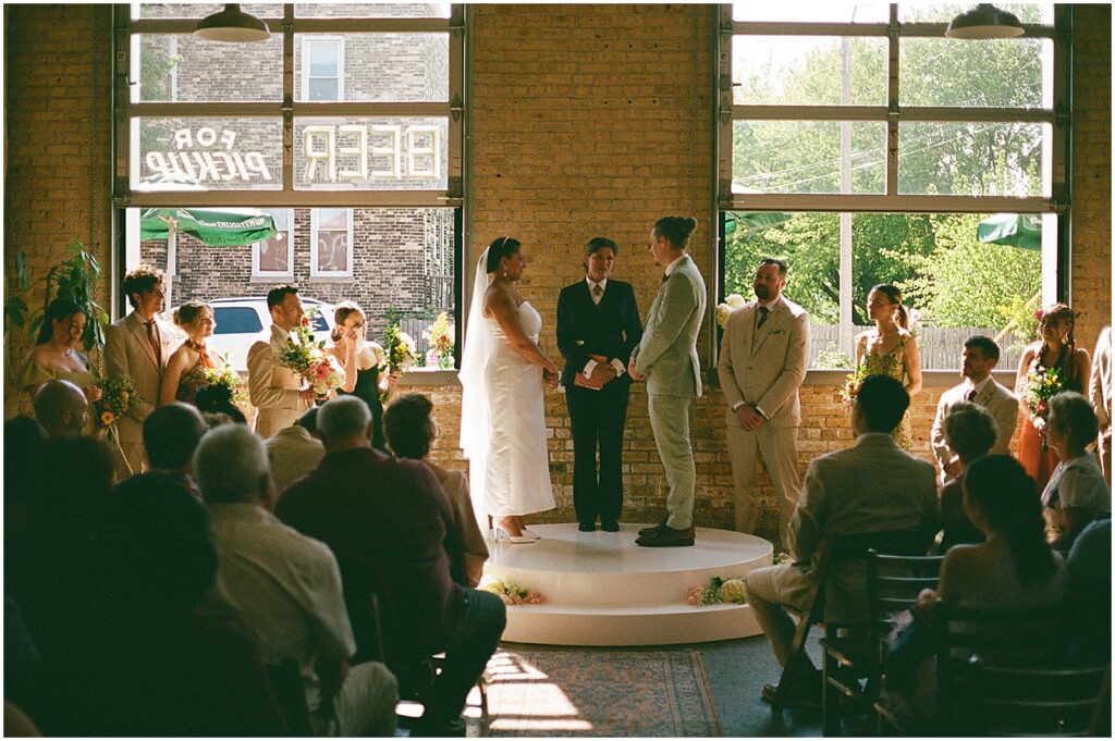 A bride and groom stand on a platform at an Enlightened Brewing Company wedding ceremony.